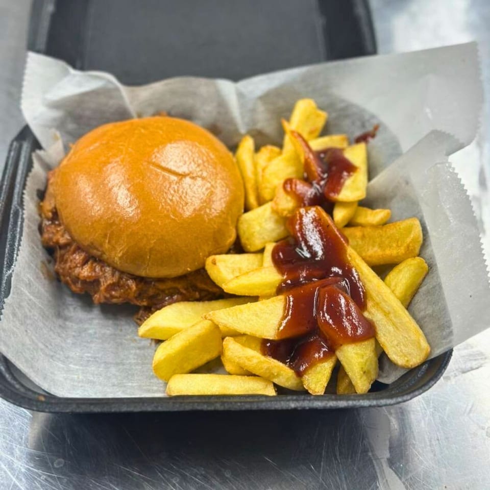 A Fisher's BBQ & Moore pulled pork sandwich with a side of fries topped with ketchup.